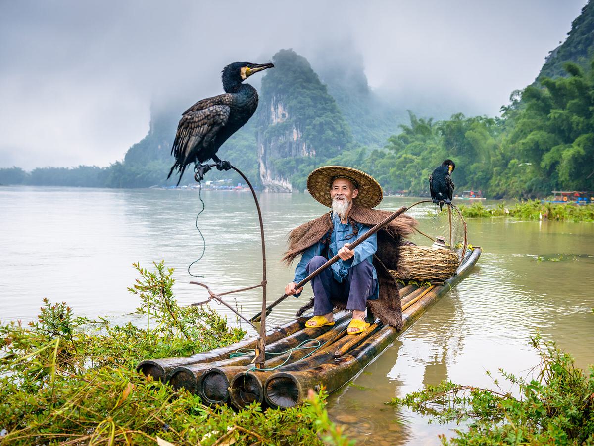Cormorant fisherman and his bird on the Li River in Yangshuo, Guangxi, China